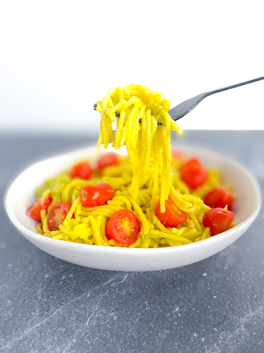 Vegan Avocado Pasta in a bowl with tomatoes with fork on top