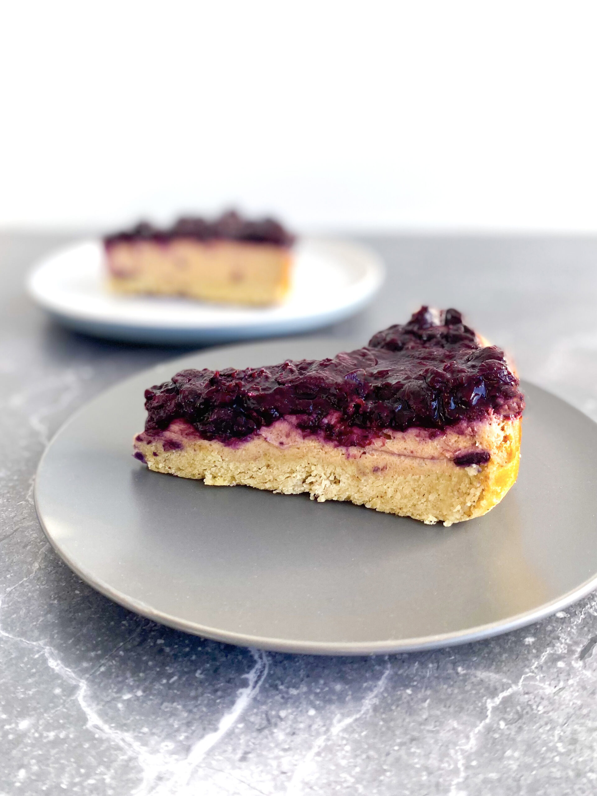 Two slices of Vegan Blueberry Cheesecake on two plates
