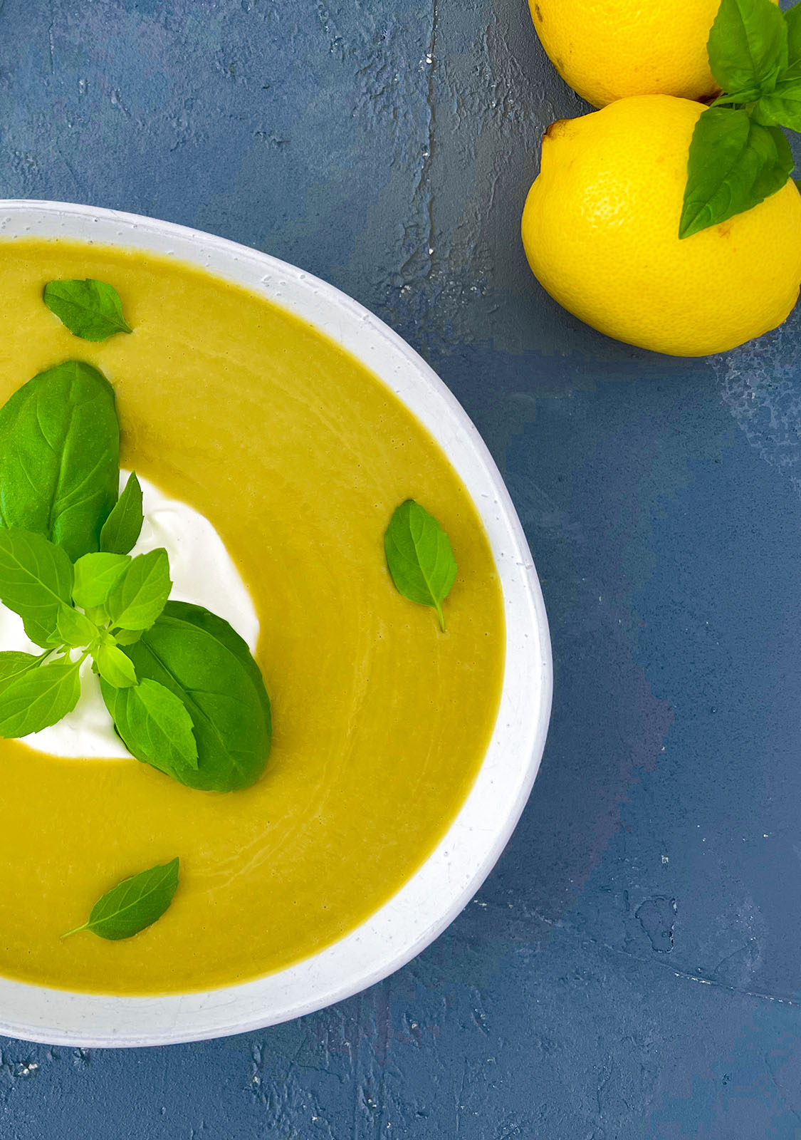 Vegan Broccoli Soup on Blue Background with Lemons and Basil