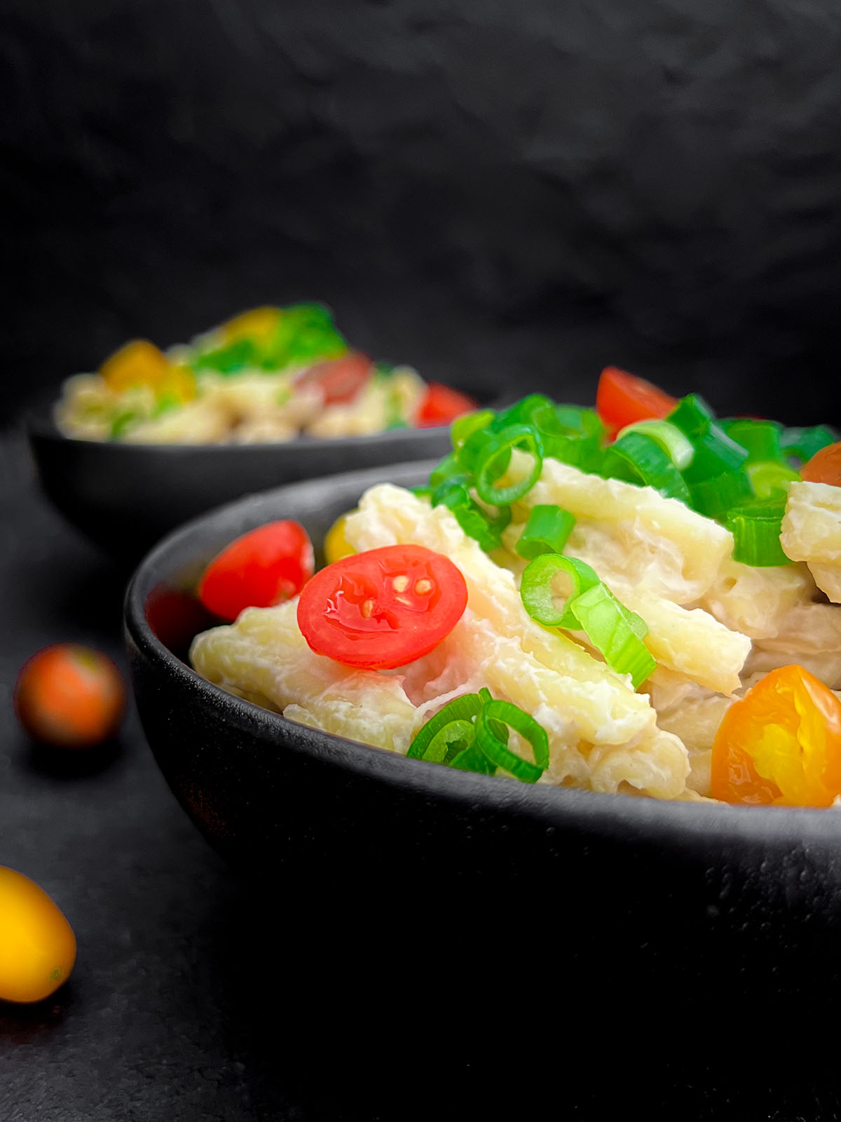 Vegan, gluten-free Cauliflower Alfredo pasta served in bowls garnished with spring onions and cherry tomatoes.